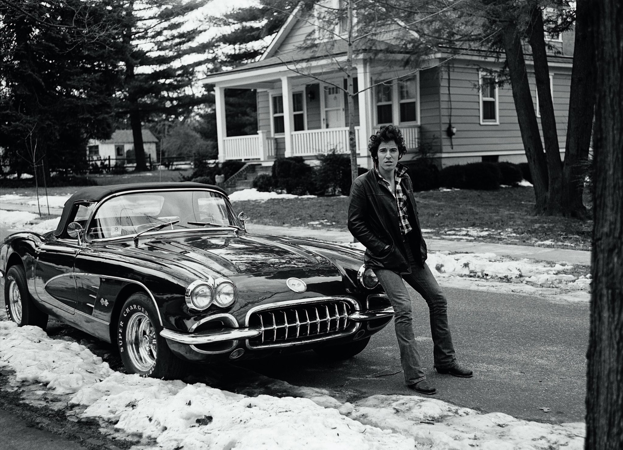Bruce Springsteen sitting on a corvette